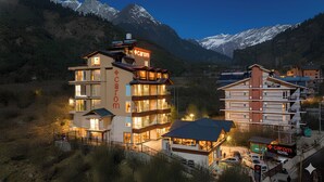 A multi-story hotel with a prominent 'Carom' sign, surrounded by mountainous terrain. - Carom Hotel Manali (Manali)