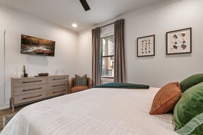 A bedroom with a large bed, a dresser, a chair, and a window with curtains.
