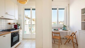 A modern kitchen with white cabinets, a gas stove, and a dining area with a table and chairs. - Bright penthouse apartment for friends and families (Firenze)