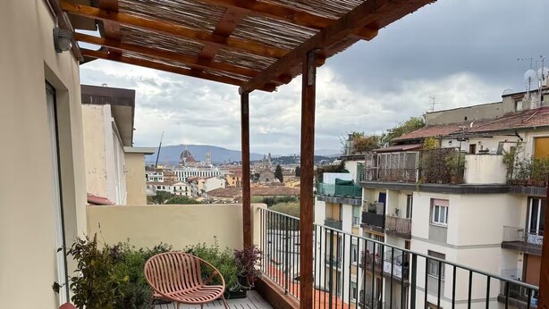 A balcony with wicker furniture, a table, and a view of the cityscape. - Bright penthouse apartment for friends and families (Firenze)