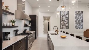 A modern kitchen with a large island, stainless steel appliances, and pendant lighting.