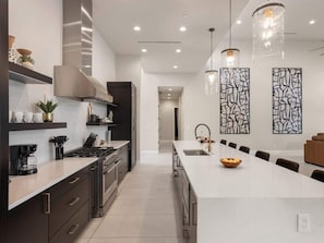A modern kitchen with a central island, built-in appliances, and pendant lighting.