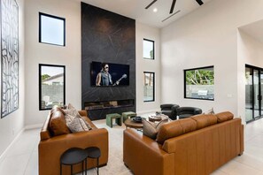 A modern living room with a fireplace, leather sofas, and a television.