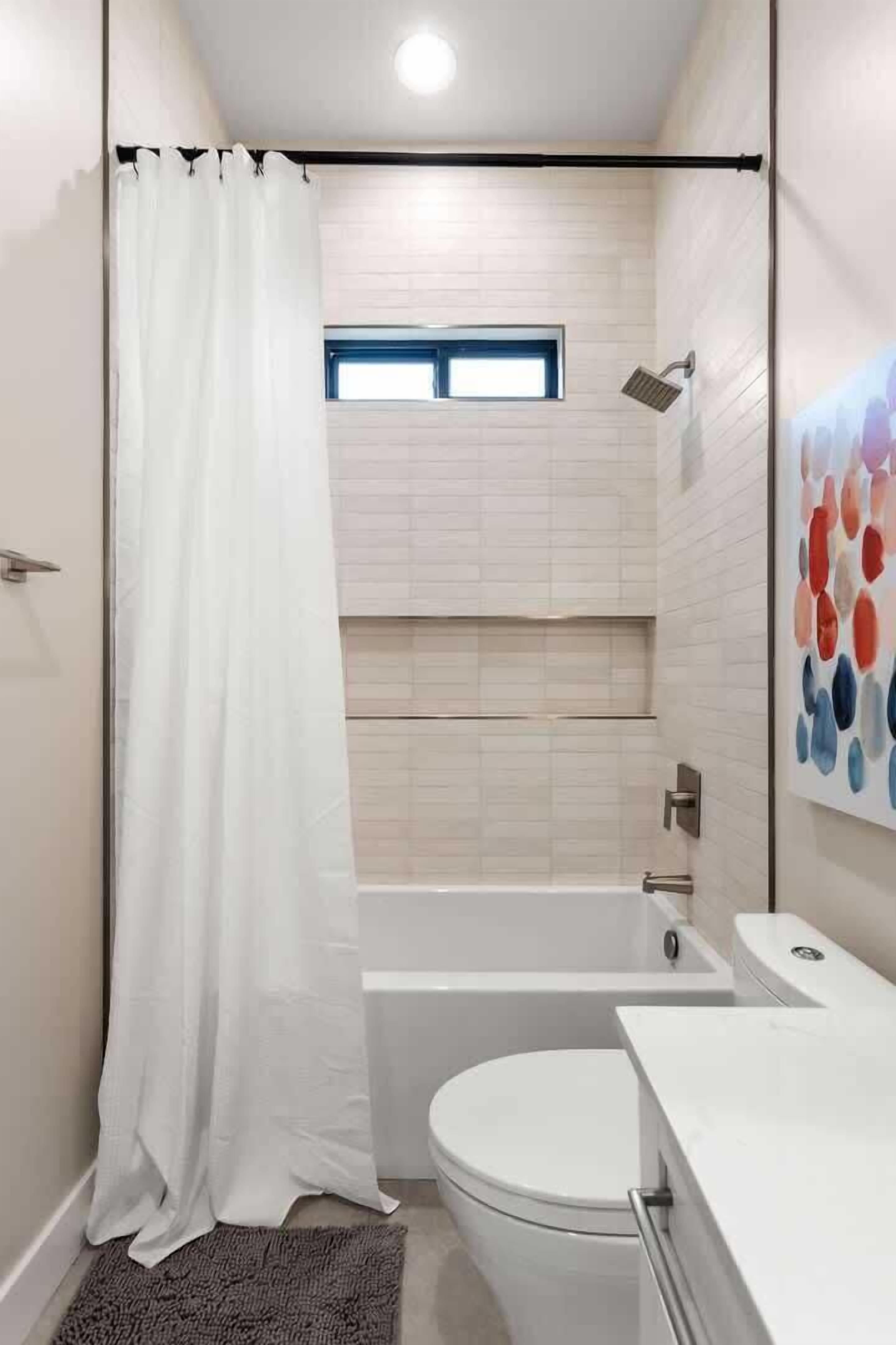 A modern bathroom with a shower, toilet, and bathtub.