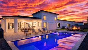 A modern house with a swimming pool, outdoor seating, and a fire pit.