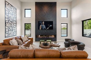 A modern living room with a fireplace, leather sofas, a TV, and artwork on the walls.
