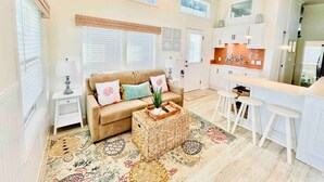 A spacious living room with a sofa, coffee table, and a kitchen area with a bar. - Vacation Cottage North Myrtle Beach (North Myrtle Beach)