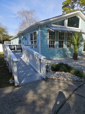 A light blue house with a covered porch and a small garden area.