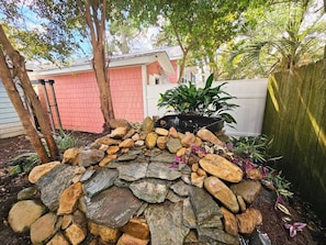 A stone garden feature with plants and a wooden ladder.