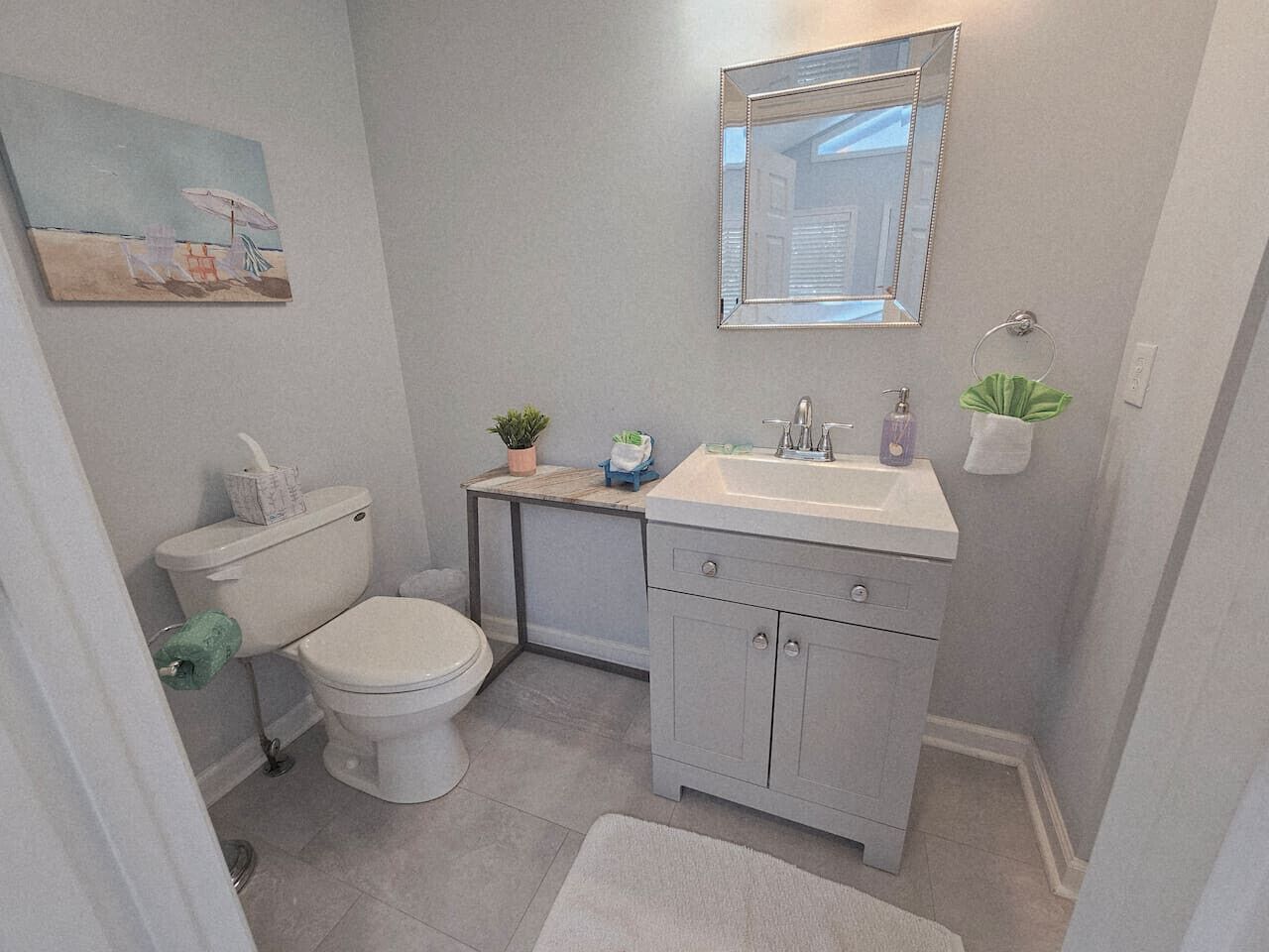 A bathroom with a toilet, sink, mirror, and a small plant on the counter.