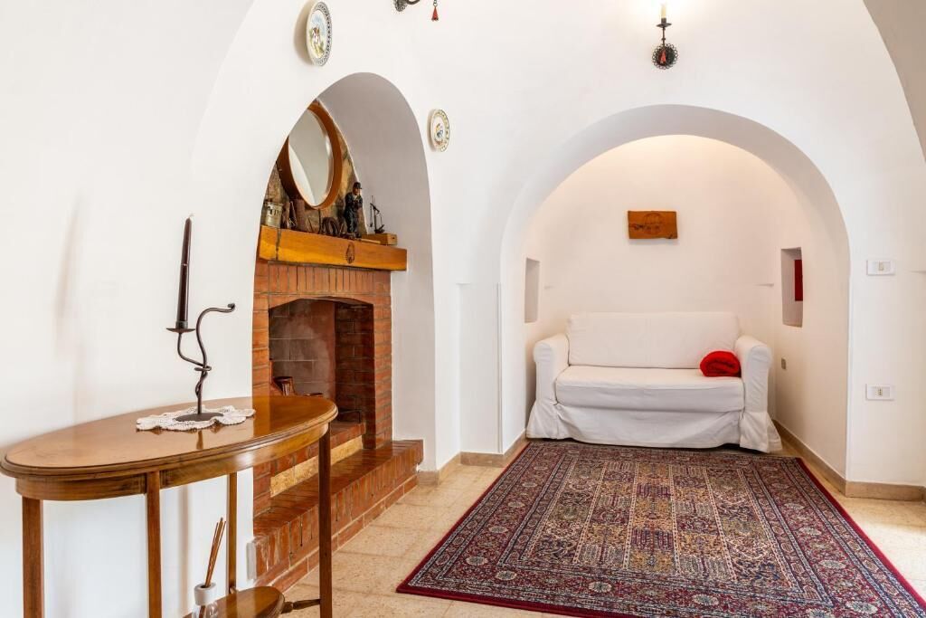 Una habitación con chimenea, un sofá blanco y una alfombra estampada.