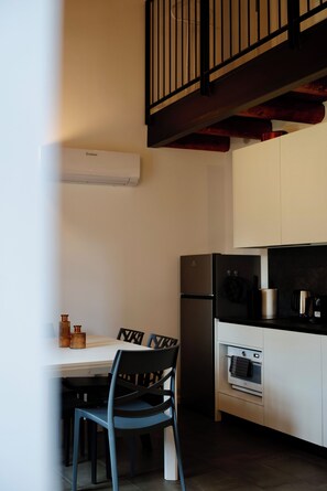 A compact kitchen with a white countertop, a black refrigerator, and a built-in oven.
