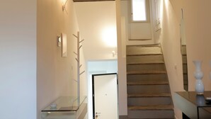 Una escala que condueix a un segon pis amb sostre de fusta i una finestra petita.