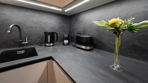 A modern kitchen with a black countertop, a coffee maker, a toaster, and a vase with a flower. - Relax apartment with private pool I (Novalja)