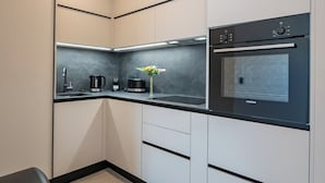 A modern kitchen with white cabinets, black countertops, a Siemens oven, and a stainless steel sink. - Relax apartment with private pool I (Novalja)