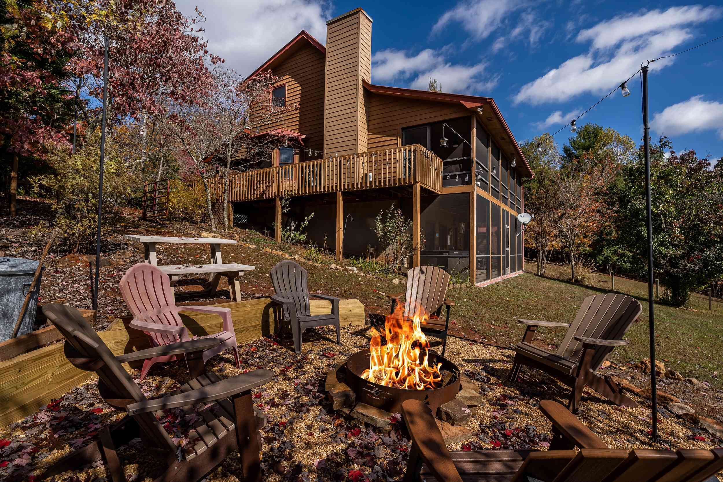 A wooden cabin with a deck, a fire pit, and outdoor seating.