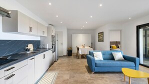 A modern kitchen with white cabinets, a blue countertop, and a dining area with a blue sofa and yellow table.