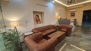 A modern living room with a brown leather sofa, a glass coffee table, and a potted plant. - Jai Hari Vilas Jodhpur (Jodhpur)