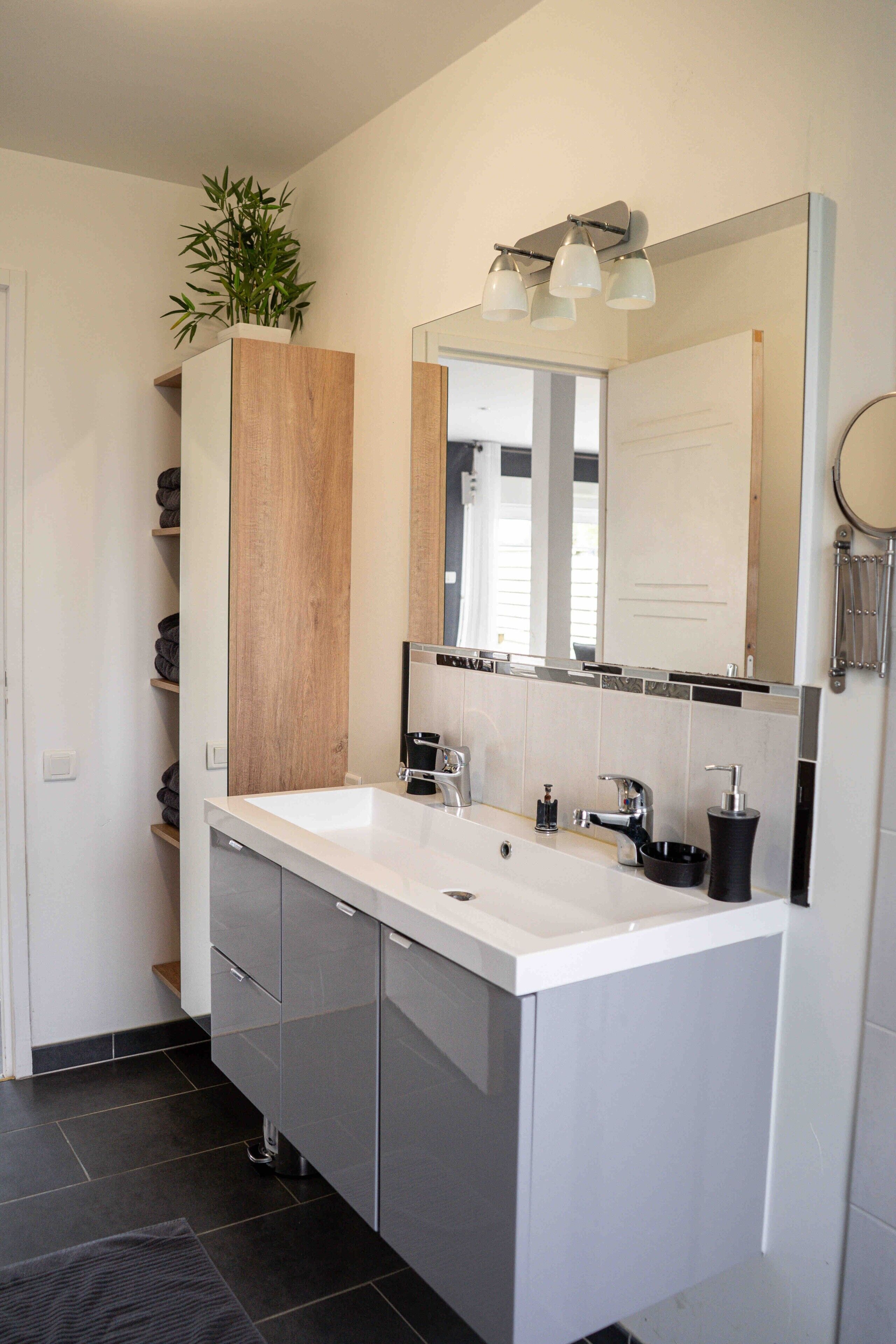 Ein modernes Badezimmer mit Waschbecken, Holzschrank und beleuchtetem Spiegel.