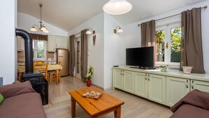 A cozy living room with a sofa, a wooden coffee table, a television, and a kitchen area with a stove and cabinets. - Holiday Home Beni with Jacuzzi by Villas Guide (Matulji)
