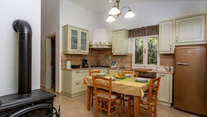 A kitchen with a stove, dining table, chairs, cabinets, and a refrigerator. - Holiday Home Beni with Jacuzzi by Villas Guide (Matulji)