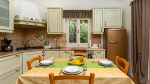 A compact kitchen with a dining area, a refrigerator, and a window with a view of greenery. - Holiday Home Beni with Jacuzzi by Villas Guide (Matulji)