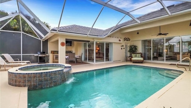 Ein Schwimmbad mit Whirlpool, Liegestühlen und einer überdachten Terrasse.