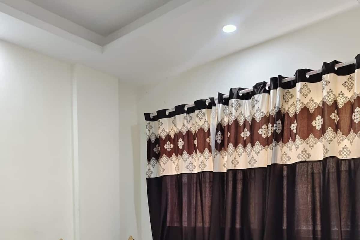 Una cama bien hecha con colcha azul, ropa de cama blanca y cabecera de madera.