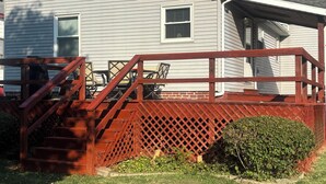 A single-story house with a red wooden deck and a small front porch.
