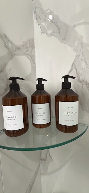 Three bottles of Finessey personal care products on a glass shelf.