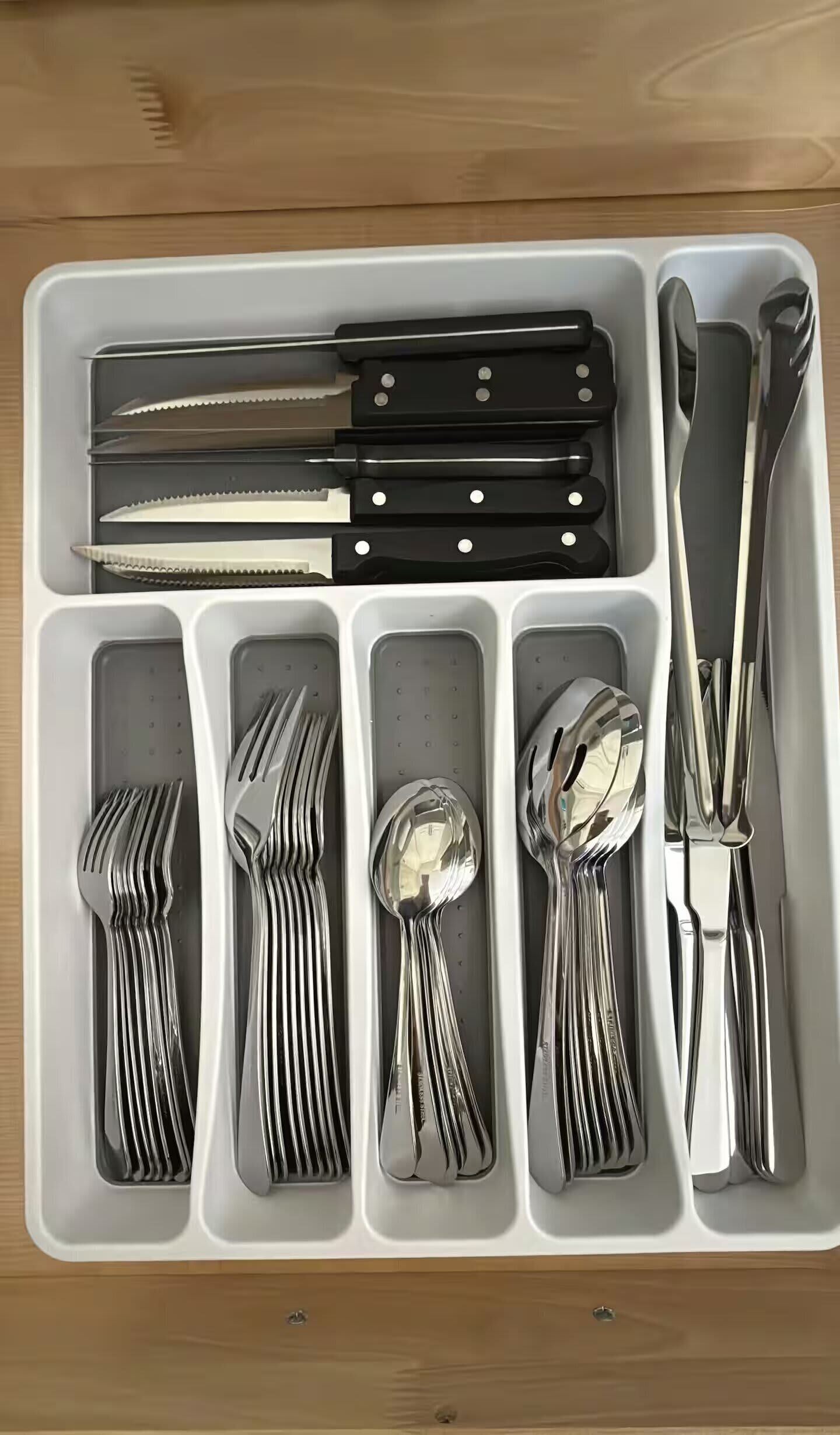 A drawer with neatly organized cutlery including forks, spoons, and knives.