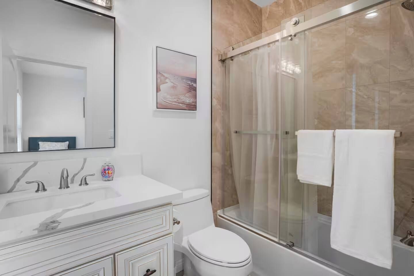 Un baño moderno con ducha de vidrio, lavamanos blanco y retrete.