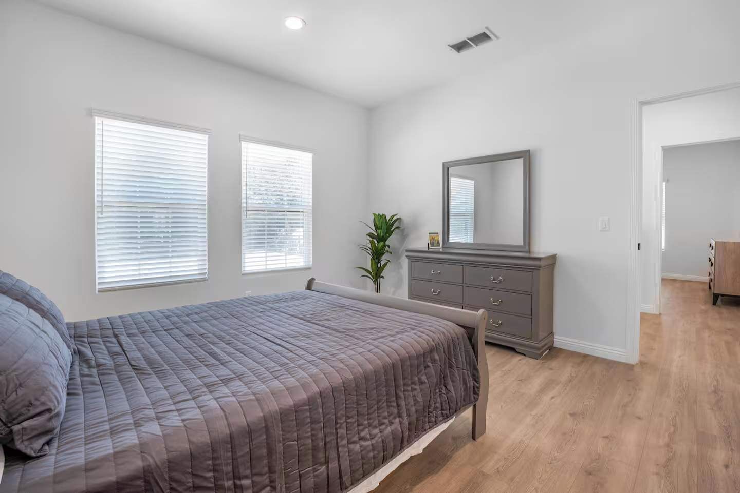 A bedroom with a bed, dresser, and a mirror.