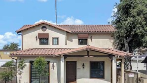 Une maison à deux étages, avec un toit en tuiles, un porche à l’avant et une pelouse bien entretenue.