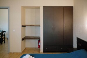 A bedroom with a bed, a wardrobe, a small shelf, and a fire extinguisher. - Seaview Retreat in Mandilada With Shared Pool (Samos)
