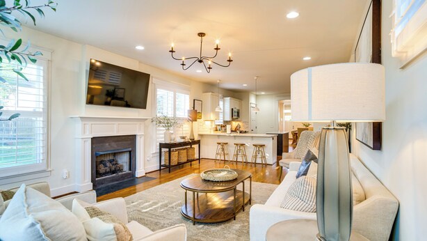 A spacious living room with a fireplace, a dining area with bar stools, and a kitchen with a large island. - Walk to 12 South: Getaway w/ Outdoor Dining! (Nashville)