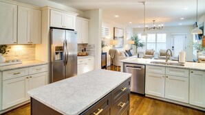 A modern kitchen with white cabinetry, a marble countertop, and stainless steel appliances. - Walk to 12 South: Getaway w/ Outdoor Dining! (Nashville)