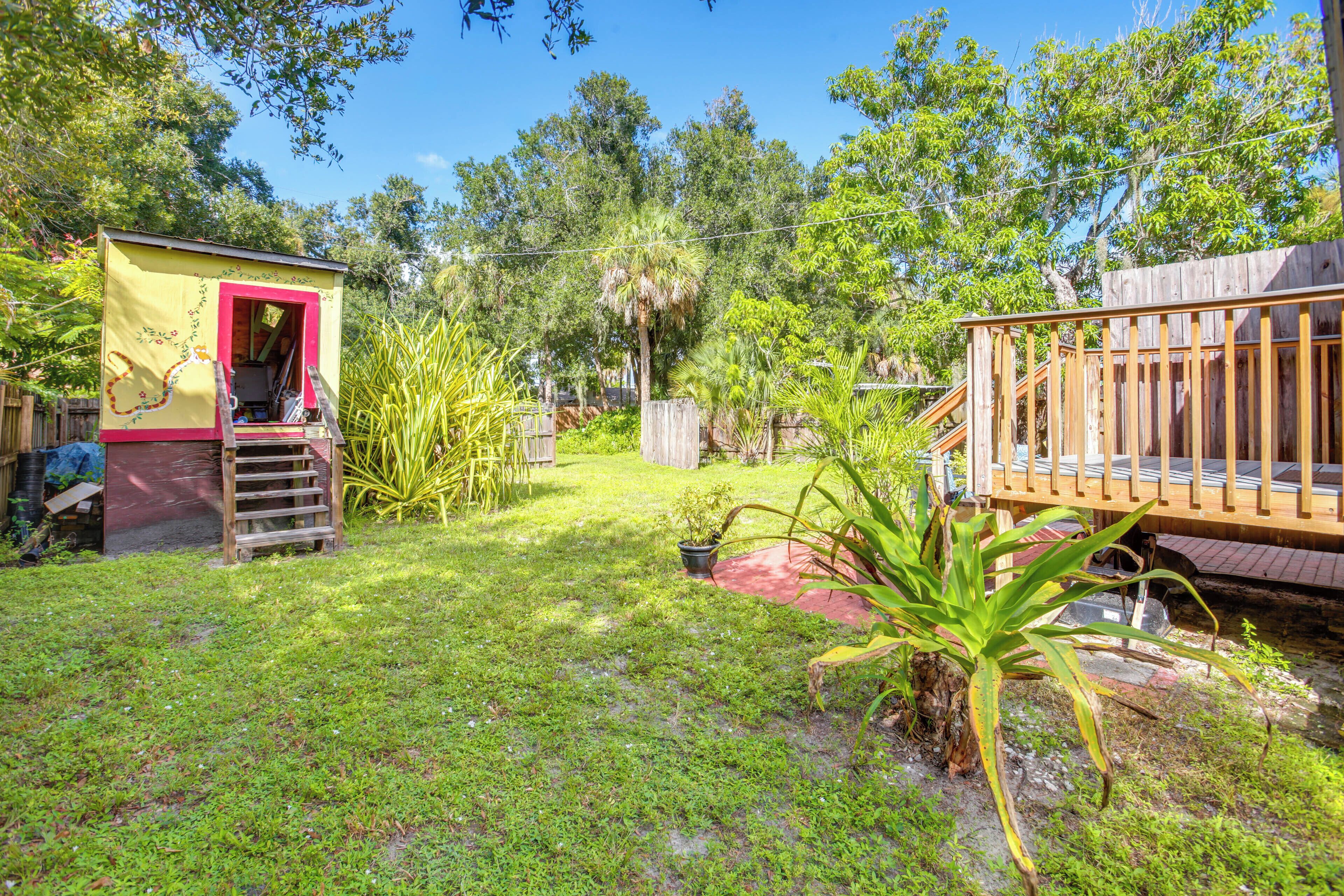 A small, enclosed outdoor area with a wooden deck and a small shed with a red door.