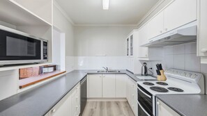 A modern kitchen with white cabinetry, a built-in microwave, a stove, and a sink.