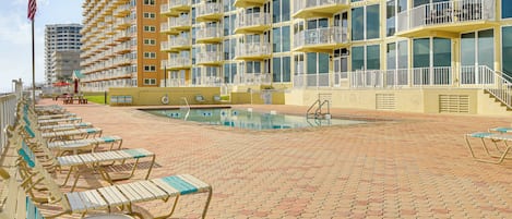 A hotel with a pool area, multiple balconies, and a flag.