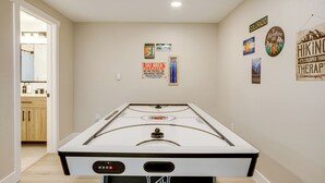 A room with a foosball table, wooden cabinets, and wall decorations including signs about Colorado and hiking therapy. - Hot Tub + Game Room: Peaceful Retreat in Evergreen (Evergreen)
