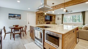 A modern kitchen with a central island, built-in oven, and a stone accent wall. - Hot Tub + Game Room: Peaceful Retreat in Evergreen (Evergreen)