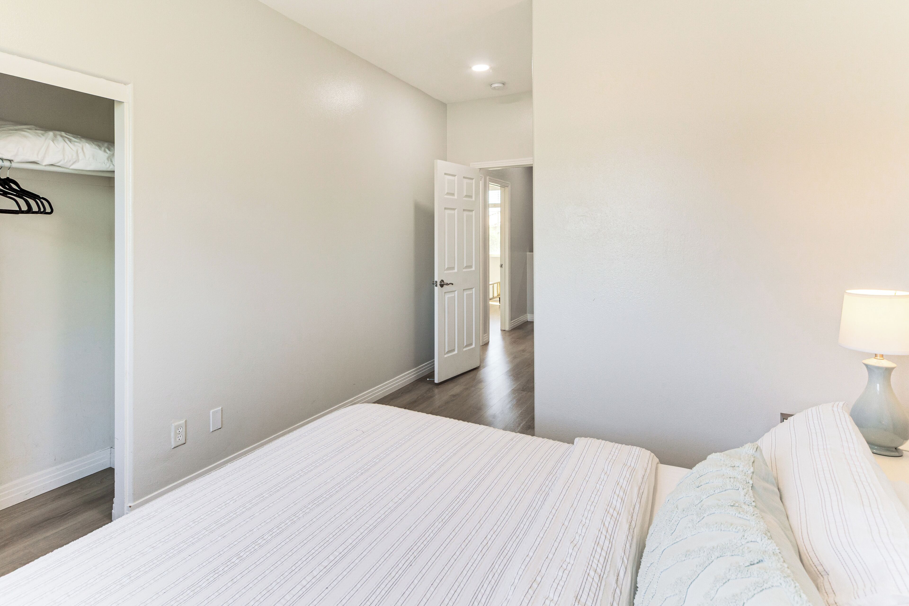 A bedroom with a bed, a nightstand, a lamp, and a closet.