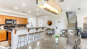 A spacious kitchen with wooden cabinets, a large island with stools, and a dining table. - Relaxing Desert Oasis, 4 Mi to Coachella Festivals (Coachella)