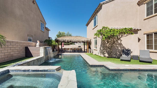 A clear swimming pool with a stone edge, a thatched-roof structure, and two lounge chairs. - Relaxing Desert Oasis, 4 Mi to Coachella Festivals (Coachella)