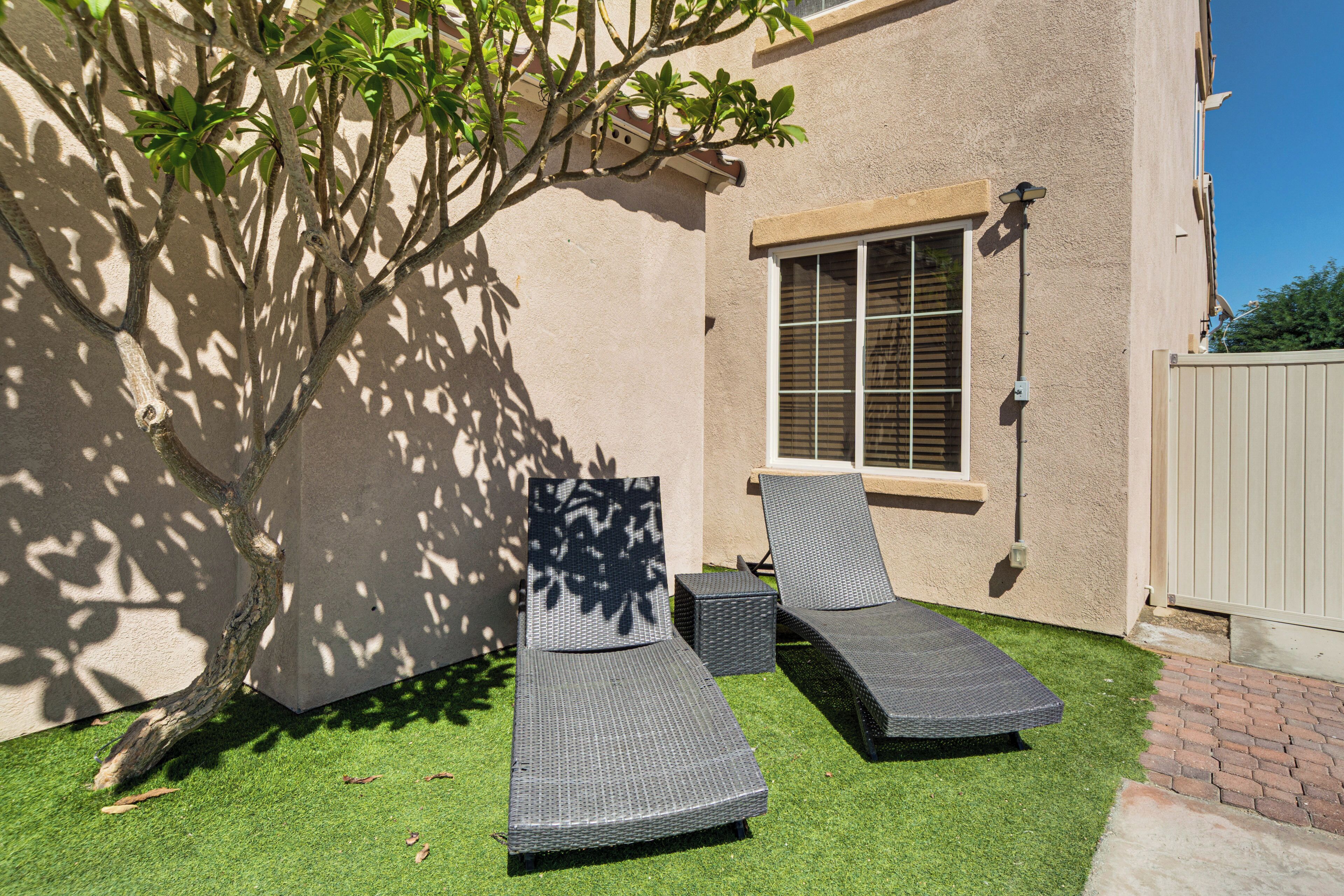Eine Terrasse mit zwei Liegestühlen und einem kleinen Baum.