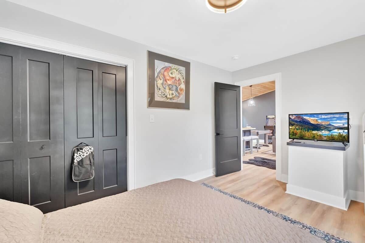 A bedroom with a bed, a wardrobe, a TV, and a painting on the wall.