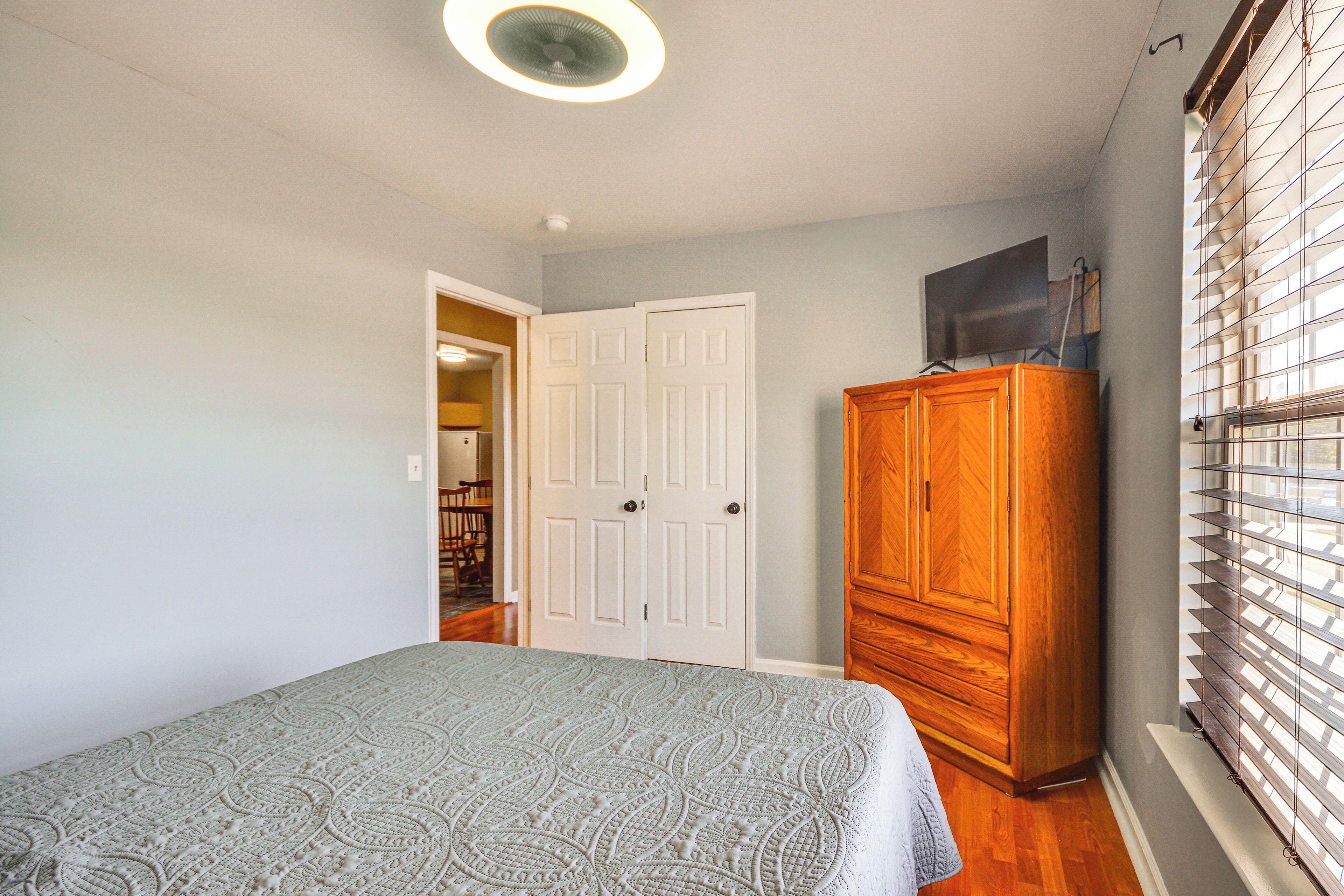 A bedroom with a bed, a wardrobe, and a door leading to a hallway.
