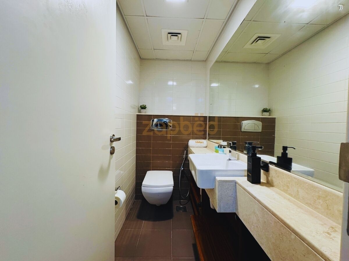 A bathroom with a toilet, sink, and mirror.