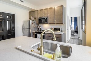 A modern kitchen with a central island, stainless steel appliances, and wooden cabinets. - Camp Washington Flat: Walk to Coffee, Bars & Dtwn (Cincinnati)